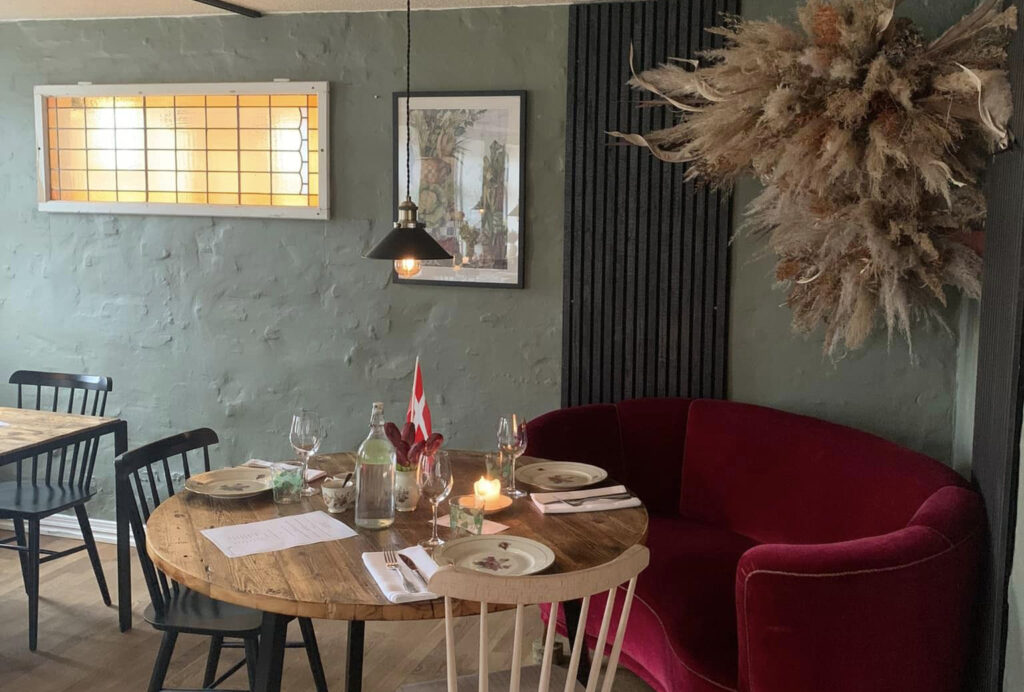 Hyggelig restaurant i Nordjylland med rustikke træborde, opdækning og bløde møbler på Essens Gaarden.