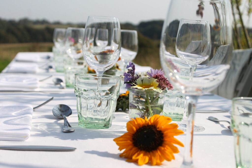 Elegant opdækket bord med blomster og vinglas i naturen på Essens Gaarden i Nordjylland.